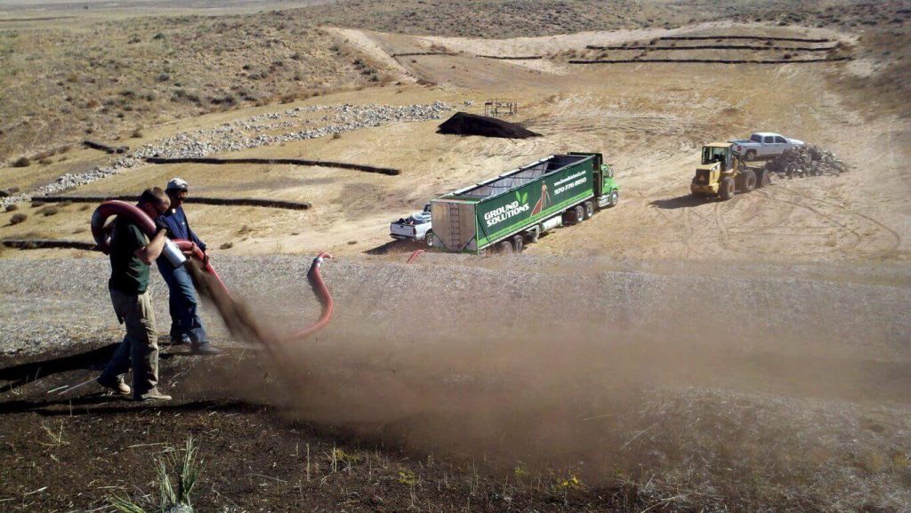 Ground Solutions placing compost blanket with seed injected on half an acre of slope in an oilfield for erosion control