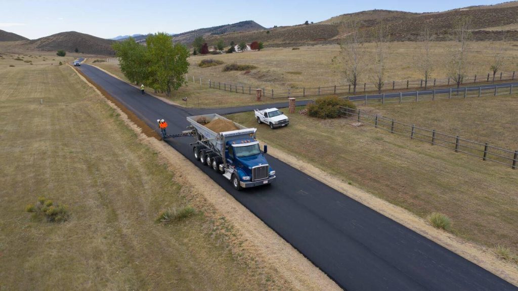 Bedrock Slingers placing roadbase along paved road for an HOA in Colorado with stone slinger truck