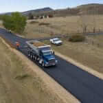 Bedrock Slingers placing roadbase along paved road for an HOA in Colorado with stone slinger truck