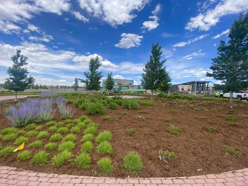 Professionally mulched commercial landscape beds at an office complex with a Ground Solutions blower truck in the background.