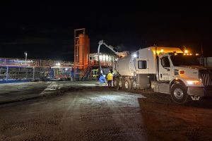 Ground Solutions hydro excavation truck performing vacuum services at an industrial site at night.